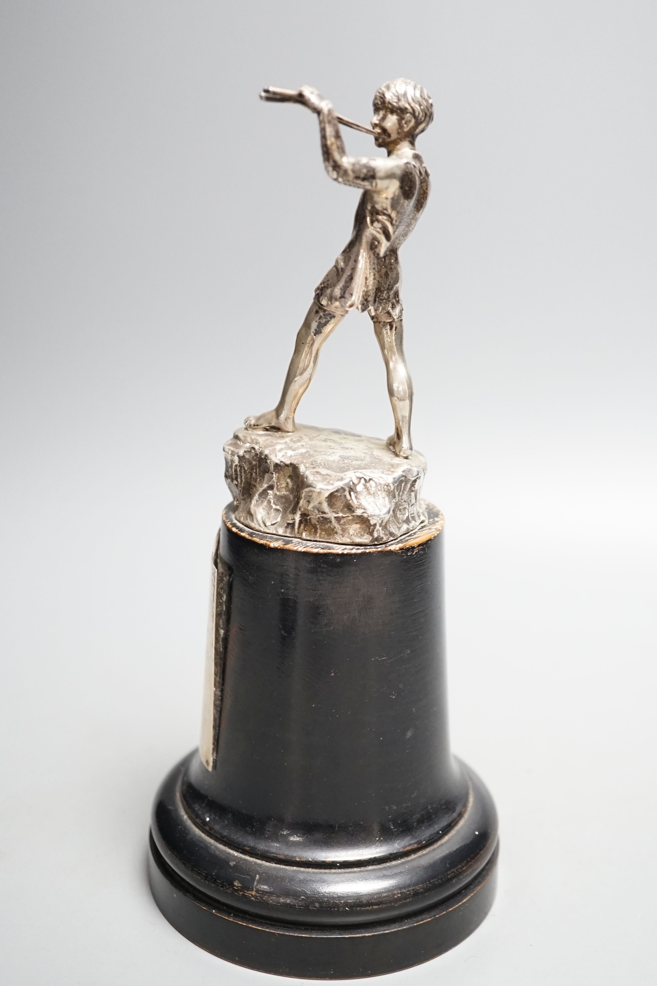 A late 1940's silver presentation figure of a young boy playing the pipes, on a rocky base, Goldsmiths & Silversmiths Co Ltd, London, 1949, on a wooden plinth with engraved presentation plaque, overall height 23.5cm